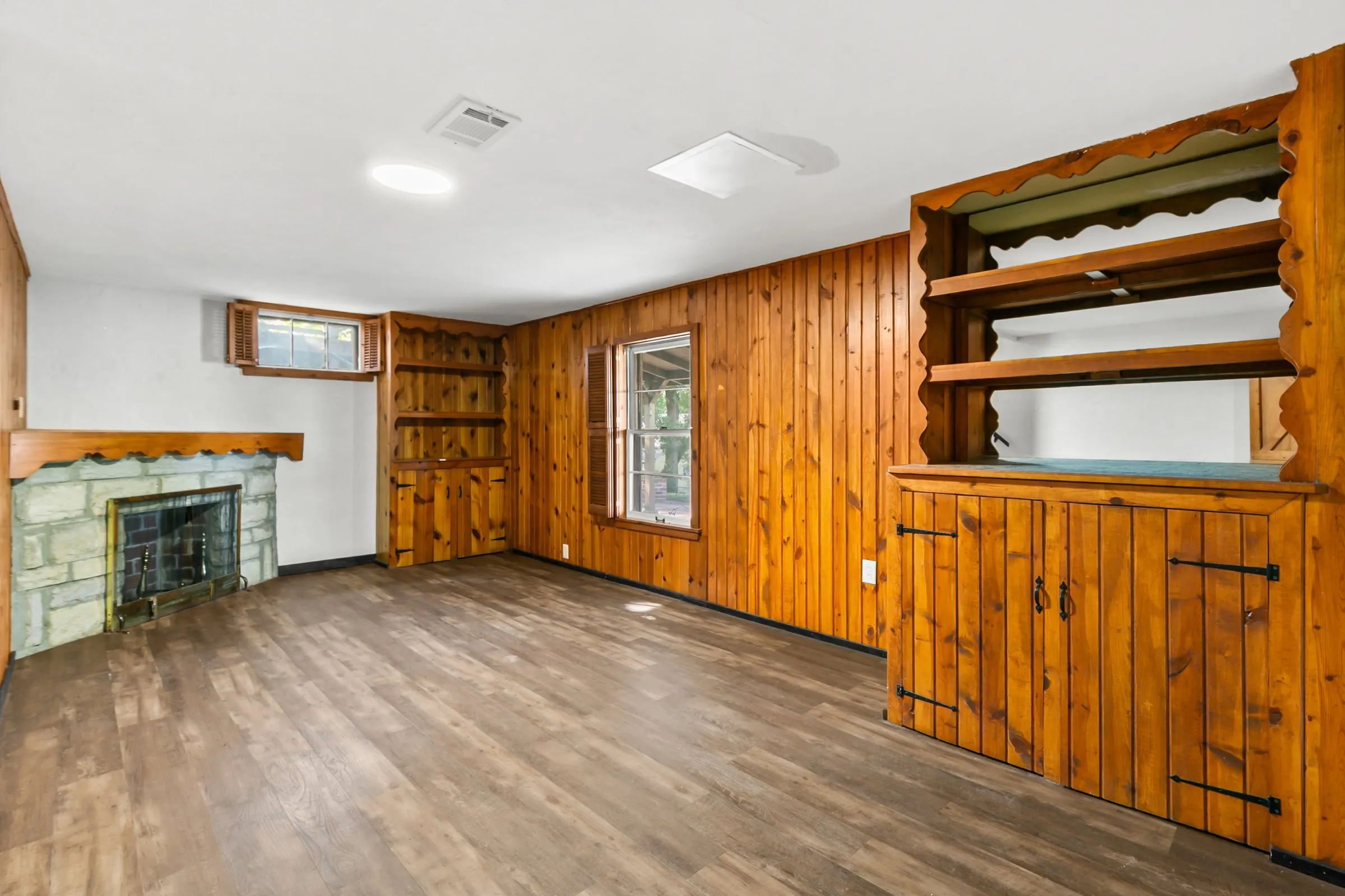 Lower-level family room with knotty pine and a stone fireplace