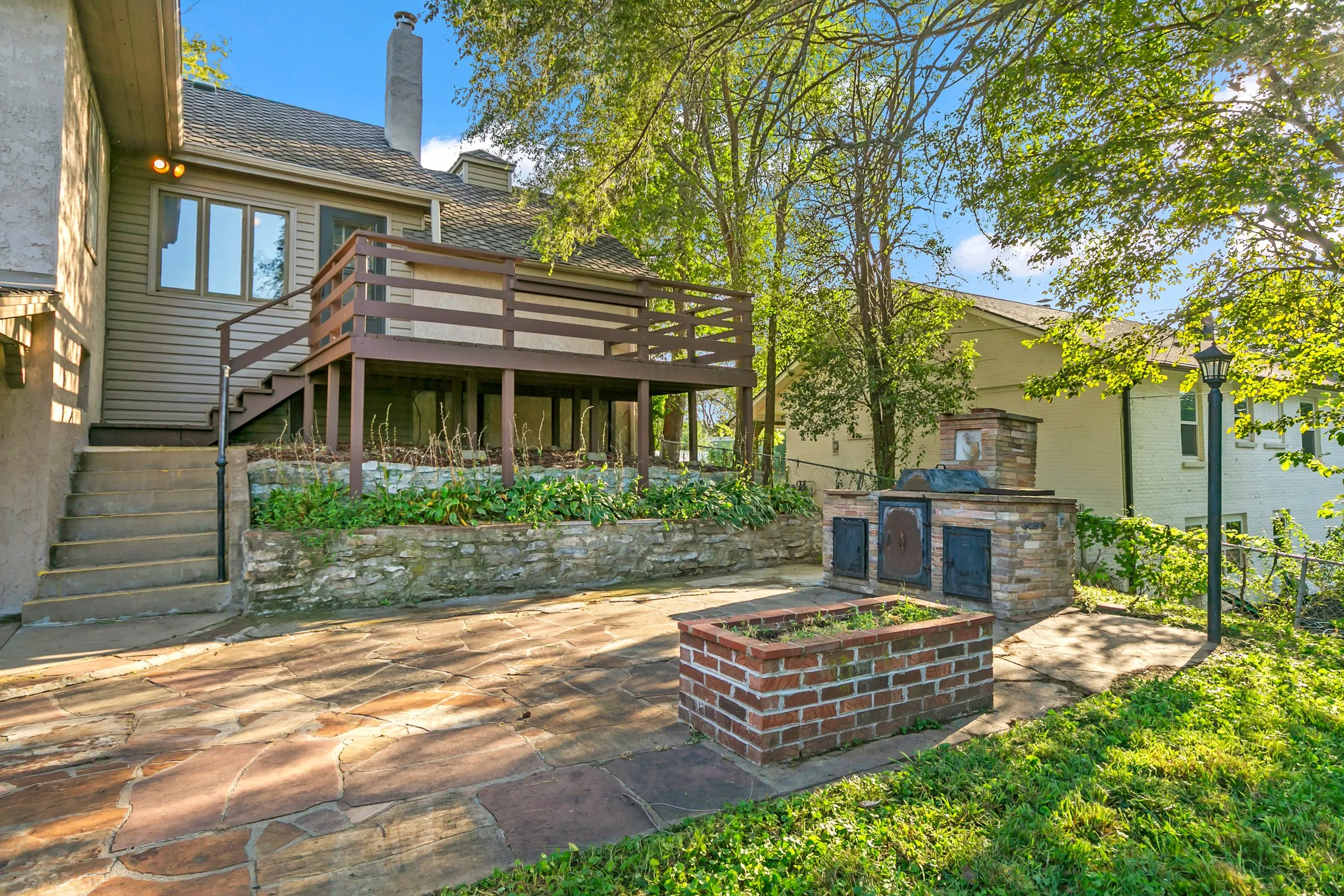 Back of the house with deck stairs down to the patio